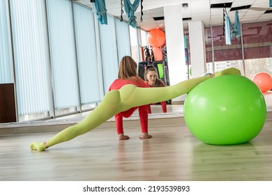 A Girl In Light Green Leggings Does Stretching In An Elite Gym In Front Of A Mirror. The Concept Of A Healthy Body In A Woman