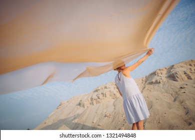 girl with a light veil and wind in the desert spread her wings