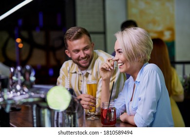 the girl likes the jokes of a stranger, caucasian guy flirt with blond girl in a pub or bar