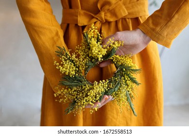 Girl In A Linen Mustard Dress Holds A Wreath With Mimosa