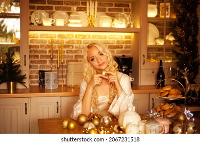 A Girl In Lingerie And A White Dressing Gown In The Kitchen Drinks Tea On Christmas Evening