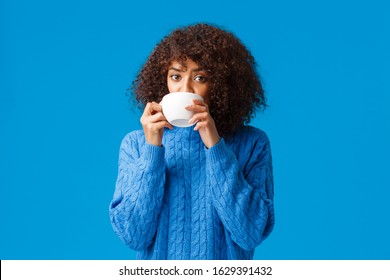 Girl listening to fresh gossips and sipping tea. Intrigued and relaxed good-looking african american woman having girlfriends meeting, drinking coffee from cup and looking camera interested