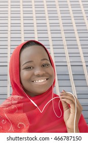 Girl listening to music and smiling in the street, thirteen years old 