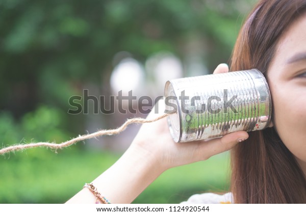 a girl listening\
through the tin can telephone, communication concept like a\
Telegram. The old days toy.