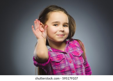 Girl Listens. Child Hearing Something, Hand To Ear Gesture On Grey Background.