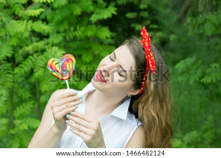 girl with a lollipop in the trees in the summer day