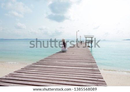 A girl lonely sitting on the wooden pier at to the sea