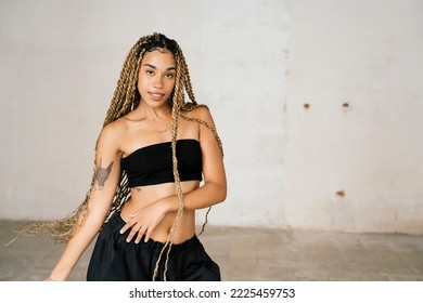 girl with long blonde braids dancing in a black tracksuit in an abandoned warehouse while smiling and enjoying her passion and exercise. - Powered by Shutterstock