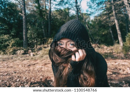 a girl with long hair and blue eyes in the mountain covering her face with her hair