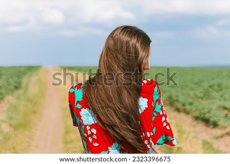 A girl with long hair walks along a dirt road.A lonely woman walks in the field.A girl walks along the road.Retro vintage photo.Gloomy atmosphere.Loneliness,thoughts and dreams.hair care.
confidence.