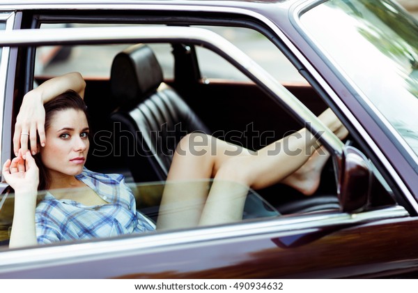 Girl with\
long legs sitting in car , tinted\
photo