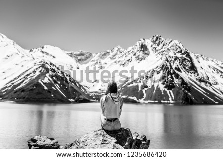 Girl looking at the amazing mountain views of the turquoise waters from the "Embalse del Yeso" (Cast Lake) close to Santiago de Chile city in Andes mountains. Snow mountains and water reflections
