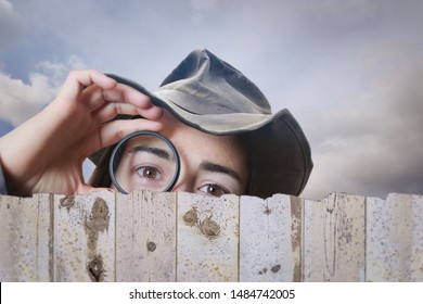 Girl With A Looking Glass Peeking Over A Fence