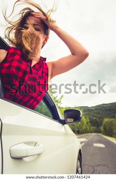 A girl is looking\
interested in the back seat in a car while someone is driving her\
in some rocky landscapes