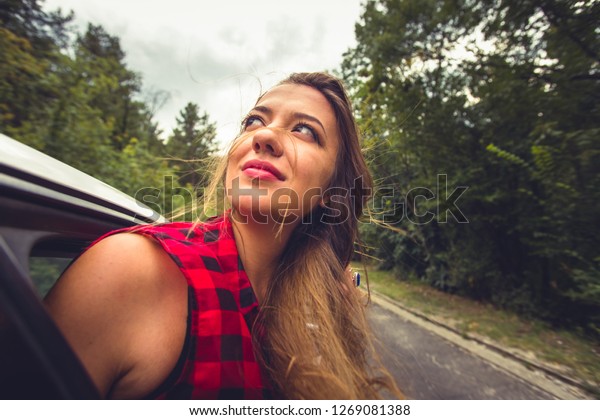 A girl is looking interested in the back\
seat in a car while someone is driving\
her