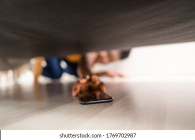 Girl Looking For Lost Mobile Phone Under Sofa