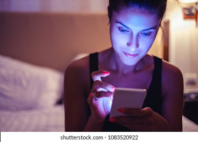 Garota olhando para o celular no quarto esmaecido