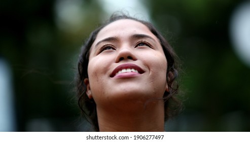 Girl looking at sky and smiling. Young woman face with HOPE and FAITH
