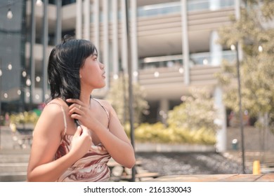 A Girl Looks Around And Strokes Her Hair Out Of Anxiety. Getting Nervous For A First Date With Someone She Met Online. At The Al Fresco Promenade Of A Shopping Mall.