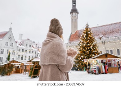 The girl looks at the decorated Christmas tree in the city square. Festive new year lights and winter mood. Christmas markets in Europe