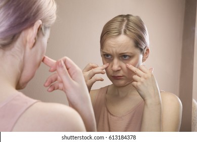 Girl Looks In The Mirror, Not Pleased With The Appearance, Pulls The Skin. Ugly, Aging Skin. Allergic To Cosmetics, Fear Of Aging, Under Eye Circles, Wrinkles. Low Self-esteem, Dysmorphic Disorder. 