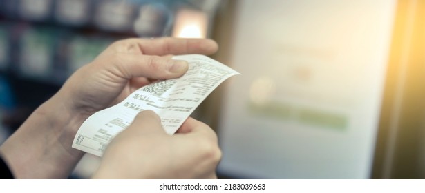 the girl looks at the receipt in the store - Shutterstock ID 2183039663