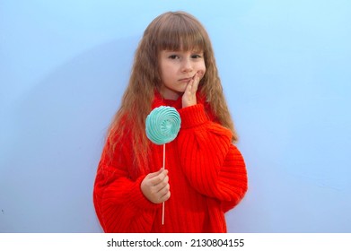 girl looks at a sweet lollipop, a child has a toothache while eating sweets. The child suffers from toothache because he ate too many sweets.