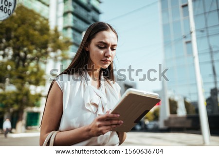 a girl looks in a tablet pc on the street of a business center,