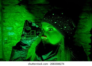 The girl looks through a night vision device in the dark.