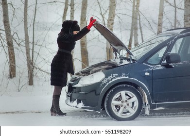 girl looks under cowl of broken car on rural road - Powered by Shutterstock