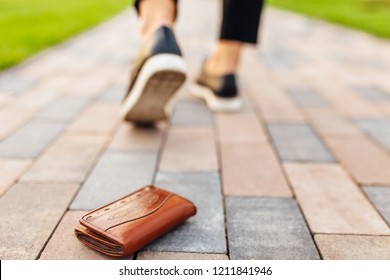 The girl lost a leather wallet with money on the street. Close-up of a purse and legs of a departing girl