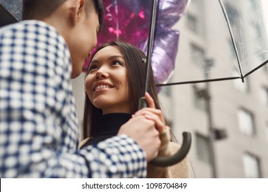 Girl in love looks at the guy under umbrella. Love story. Romantic concept