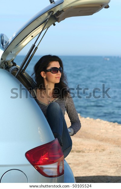 The girl\
in a luggage carrier of the car at the\
sea