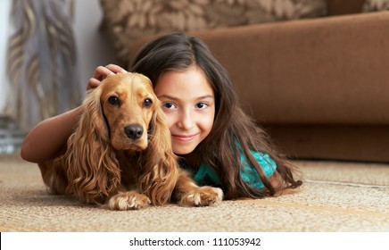 The girl is lying in the floor with the dog