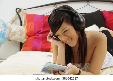 Girl Lying On Bed, Holding CD Case, Listening To Headphones