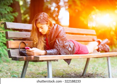 Girl Lying On A Bench Using Whats-app