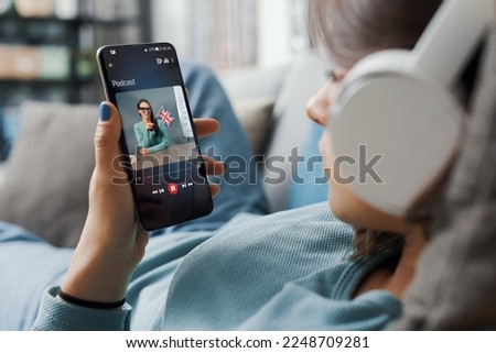 Girl lying on the couch at home and connecting with her smartphone, she is learning English online