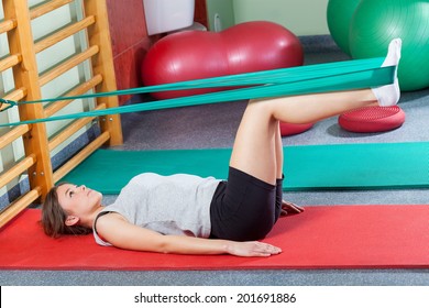 Girl Lying On Exercise Mat And Stretching Legs With Elastic Band