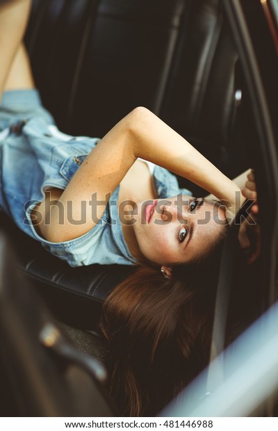 Girl lying on\
leather seat of car. tinted\
photo