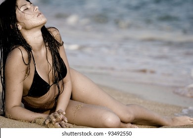 The girl lying on the sand at the beach with your eyes closed