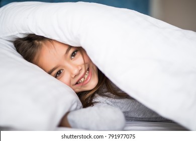 girl lying under a blanket in the bed and smiling