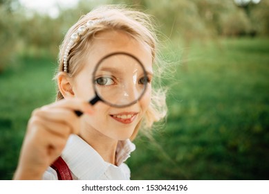 girl with magnifying glass on the street in the daytime, children play outdoors