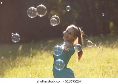 A Girl Makes Big Soap Bubbles In The Park