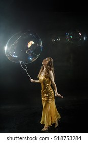 A Girl Makes Big Soap Bubbles In A Black Studio