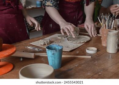a girl makes clay products in a pottery workshop, her teacher helps her - Powered by Shutterstock