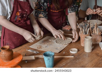 a girl makes clay products in a pottery workshop, her teacher helps her - Powered by Shutterstock