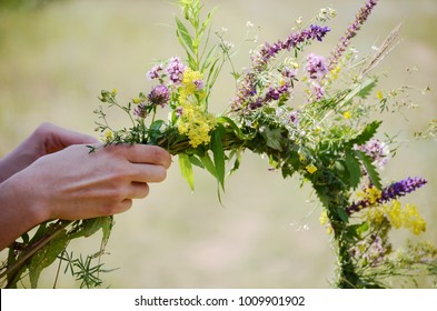 The Girl Makes A Wreath At The Head. The Process Of Weaving A Wreath With Herbs And Wild Flowers. Summer. Spring