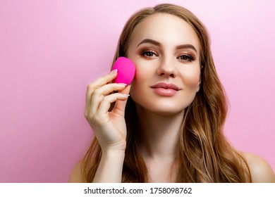 Girl With A Makeup Beauty Blender On A Pink Background