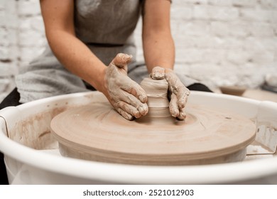 Girl is making a bowl on a pottery wheel with your own hands. Forming the proper size and shape of pottery with increasing speed of a pottery wheel - Powered by Shutterstock