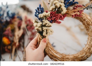 Girl making floral door wreath from colorful dry summer flowers and plants.  Fall flower decoration workshop